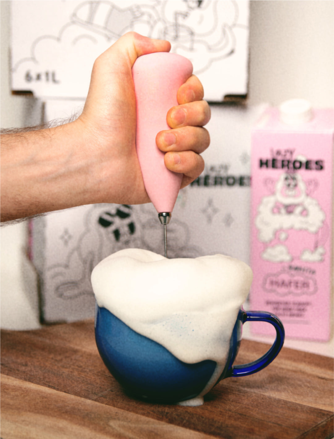 Eine Person gießt eine rosa Hafer Barista-Flüssigkeit in eine Tasse von Lazy-Heroes.