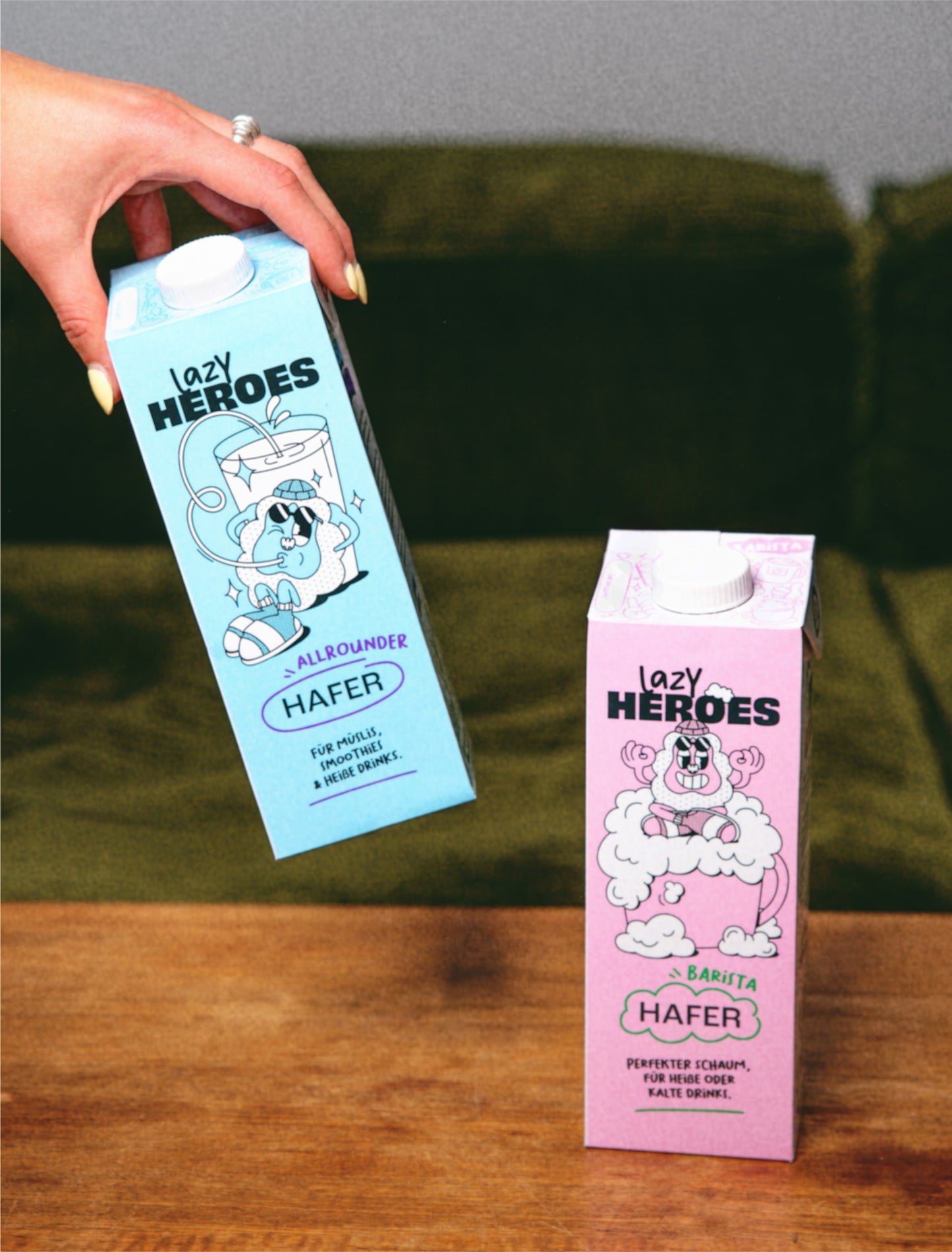 Eine Person hält einen Karton Hafer Mix neben einer Couch der Lazy Heroes GmbH.